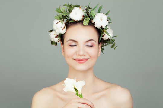 Beautiful young woman model with clear skin and cotton flowers crown. Skincare and facial treatment concept