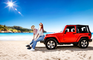 Summer time on beach and two young people with red summer car. 
