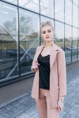 Obraz premium Beautiful successful young businesswoman outdoors near glass window standing in fashionable sun glasses and modern look. Beauty, success, bussines concept