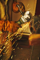 Close-up of worker cutting metal with grinder.