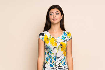 Obraz premium Teenager girl with floral dress making doubts gesture looking side