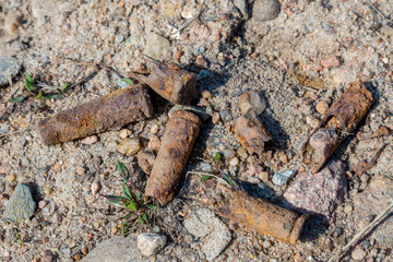 Old rusty submachine gun shells in the sand on the territory of the former shooting range in Kronstadt.