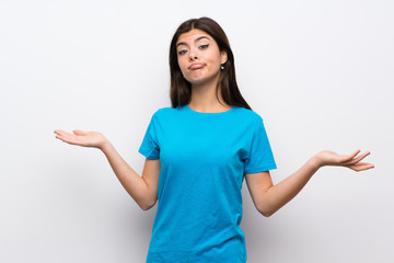 Teenager girl with blue shirt having doubts while raising hands