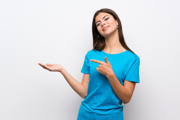 Teenager girl with blue shirt holding copyspace imaginary on the palm to insert an ad