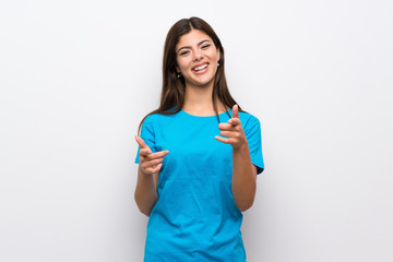 Teenager girl with blue shirt pointing to the front and smiling