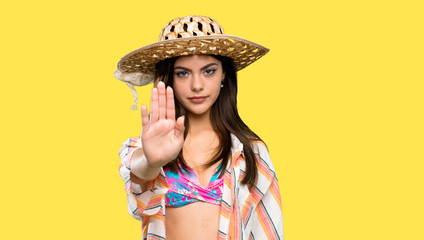 Teenager girl on summer vacation making stop gesture over isolated yellow background