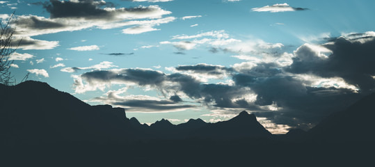 Mountain silhouette, sun down with a cloudy, blue sky