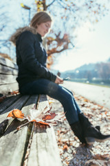 Woman is sitting on a park bench, autumn