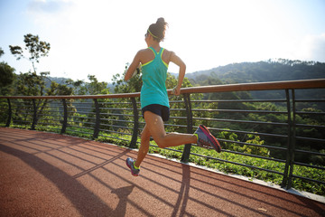 Runner athlete running on spring forest trail. woman fitness jogging workout wellness concept.