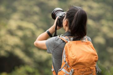 woman photographer taking photo on morning mountain forest