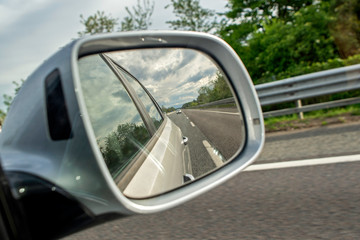 Closeup of a rear view mirror, empty road in the mirror