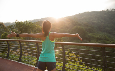 Runner athlete open arms on spring forest trail. woman fitness jogging workout wellness concept.