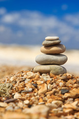 Stone pyramide on shore on blurred blue background