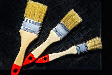Three new brushes lay in a black roller tray ready for work DIY