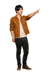 Naklejka premium A full-length shot of a Asian man with brown jacket pointing away over isolated white background