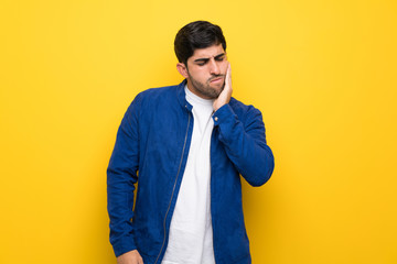 Man with blue jacket over yellow wall with toothache