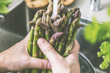 Mann beim Waschen von frischem Spargel in der Spüle.