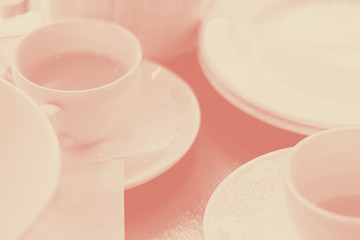 white cups of yellow sandhorn tea on wooden table sufounded by dishes, Selective focus, coral, duotone