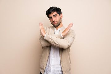 Young man over isolated wall making NO gesture