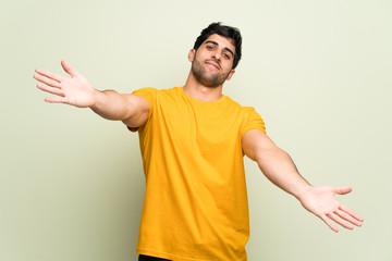 Young man over pink wall presenting and inviting to come with hand