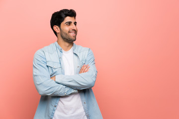 Young man over pink wall happy and smiling