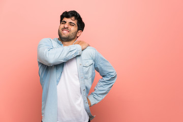 Young man over pink wall suffering from pain in shoulder for having made an effort