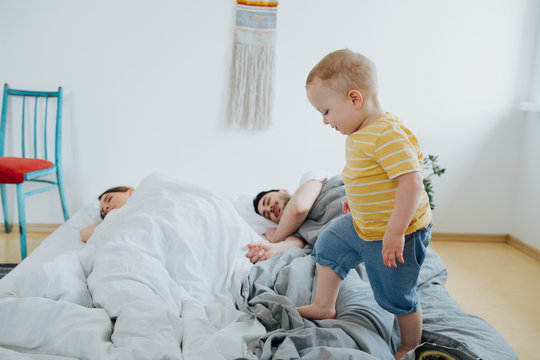 Cute little son trying to wake up his parents.
