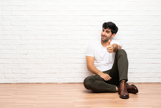 Young man sitting on the floor with thumbs up because something good has happened