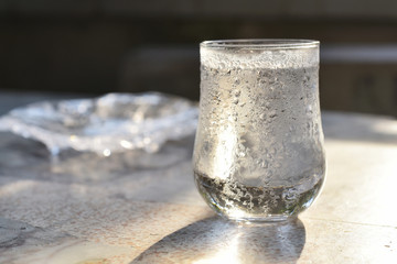 Glass of drinking water with cold frozen water drop incedent the evening sun light