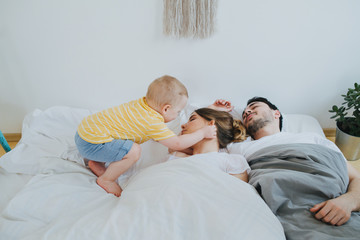 Cute little son trying to wake up his parents.