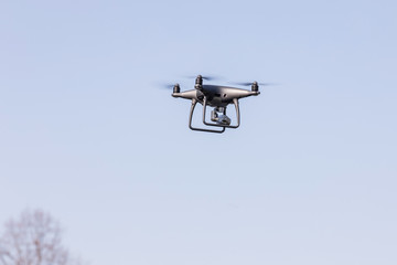 Landing a droned hand with spinning propellers. Flying drone on blue sky.