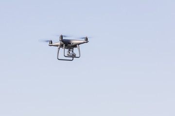 Landing a droned hand with spinning propellers. Flying drone on blue sky.