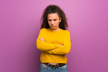 Teenager girl over purple wall feeling upset