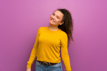 Teenager girl over purple wall smiling