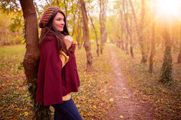 Fototapeta na wymiar Beautiful girl in stylish fall fashion clothes in park scenery, in nice warm autumn sunlight. Gorgeous romantic young woman outdoors. American plan shot in natural light, retouched, vibrant colors