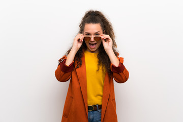 Teenager girl with coat with glasses and surprised