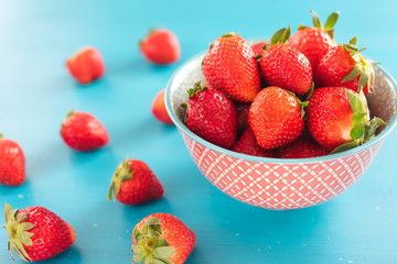 colorful ripe strawberries in a bright bowl on a blue background