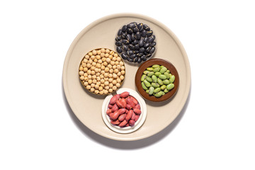 Dry peanuts and variety of beans in plate isolated on white background