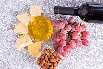 Snacks with wine - bottle, various types of cheeses, figs, nuts, honey, grapes