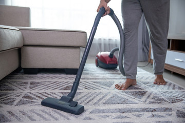 man hand vacuuming carpet at home