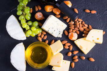Snacks with wine - bottle, various types of cheeses, figs, nuts, honey, grapes
