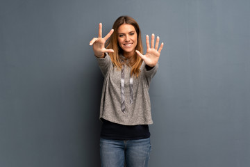Blonde woman over grey background counting eight with fingers