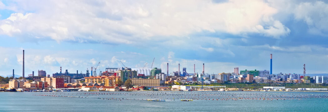 Panoramic view of Taranto, Puglia, Italy, old town with steel plant, cover of mining parks and petrochemical industry immediately behind, sunset on the sea