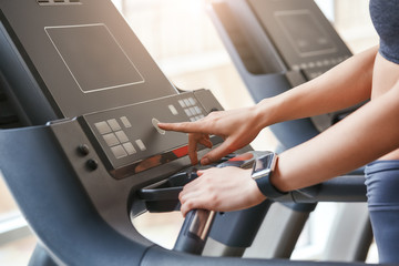 Starting to run. Close up photo of woman in sportswear pushing a start button on treadmill at gym. Cardio workout