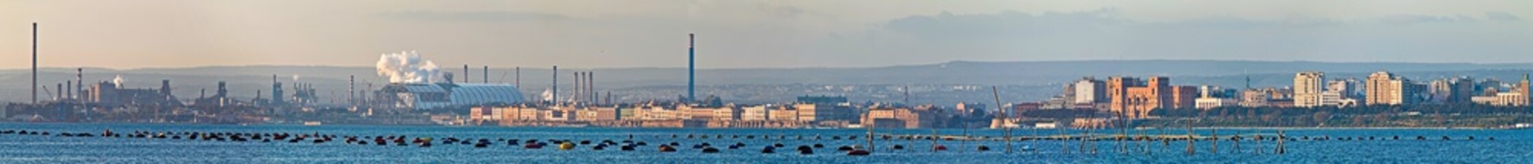 Fototapeta na wymiar Panoramic view of Taranto, Puglia, Italy, old town with steel plant, cover of mining parks and petrochemical industry immediately behind, sunset on the sea