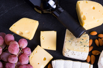 Snacks with wine - bottle, various types of cheeses, figs, nuts, honey, grapes