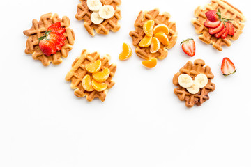 Breakfast with Belgian waffles with strawberry, tangerine and banana topings on white background top view mockup