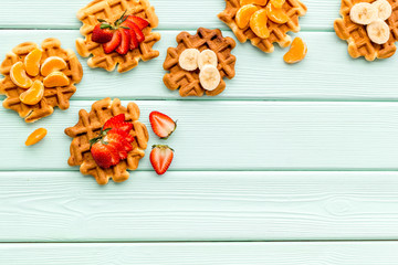 homemade Belgian waffles with fruit topings on mint green wooden background top view space for text