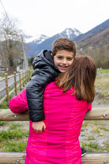 Fototapeta premium Mother and son hugging on a fence in the countryside