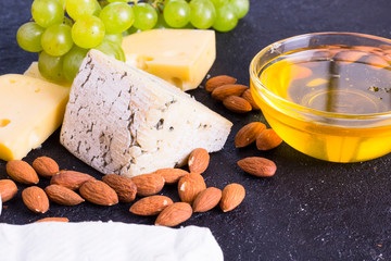Snacks with wine - various types of cheeses, figs, nuts, honey, grapes